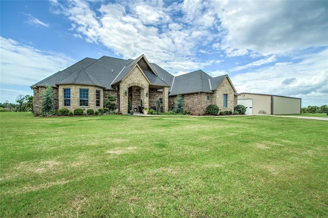 15936 SW 12th St, Yukon, OK 73099 - french country style house featuring stone siding, a front yard, a detached garage, and a shingled roof