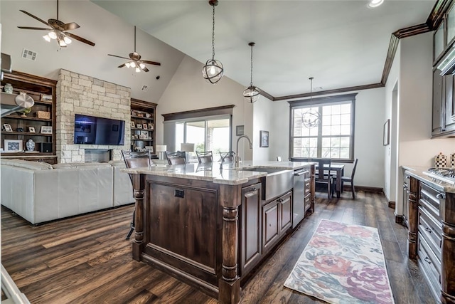 15936 SW 12th St, Yukon, OK 73099 - kitchen with a ceiling fan, dark wood-style floors, dark brown cabinetry, built in shelves, and light stone counters