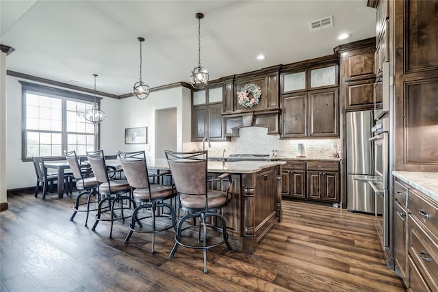 15936 SW 12th St, Yukon, OK 73099 - kitchen with ornamental molding, a breakfast bar area, dark brown cabinetry, decorative backsplash, and recessed lighting