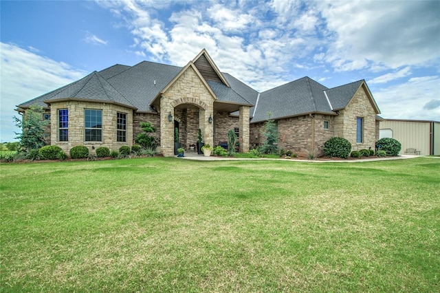 15936 SW 12th St, Yukon, OK 73099 - french provincial home with stone siding, a front yard, and a shingled roof