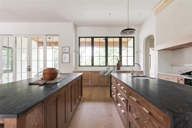 3005 Bee Hive Way, Jones, OK 73049 - kitchen featuring a spacious island, light wood-type flooring, arched walkways, french doors, and dark stone counters