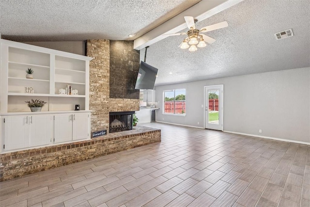 1909 Magnolia Ln, Edmond, OK 73013 - unfurnished living room featuring a textured ceiling, ceiling fan, lofted ceiling, a brick fireplace, and wood finished floors