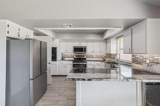 1909 Magnolia Ln, Edmond, OK 73013 - kitchen with appliances with stainless steel finishes, wine cooler, a peninsula, backsplash, and white cabinets