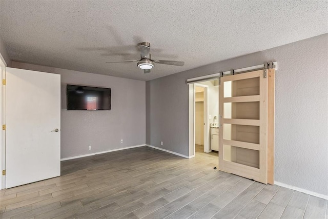 1909 Magnolia Ln, Edmond, OK 73013 - unfurnished room featuring a ceiling fan, wood finished floors, a textured ceiling, and a barn door