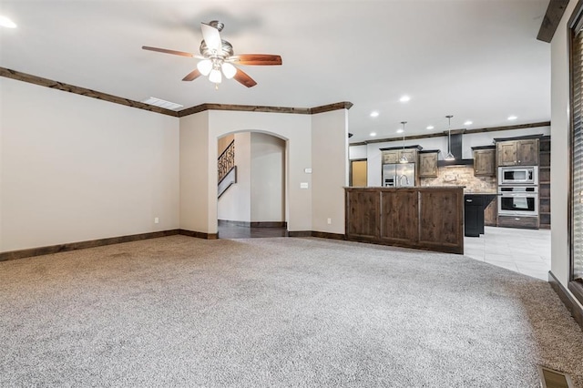 413 Branch Line Rd, Yukon, OK 73099 - unfurnished living room with arched walkways, a ceiling fan, recessed lighting, light carpet, and crown molding