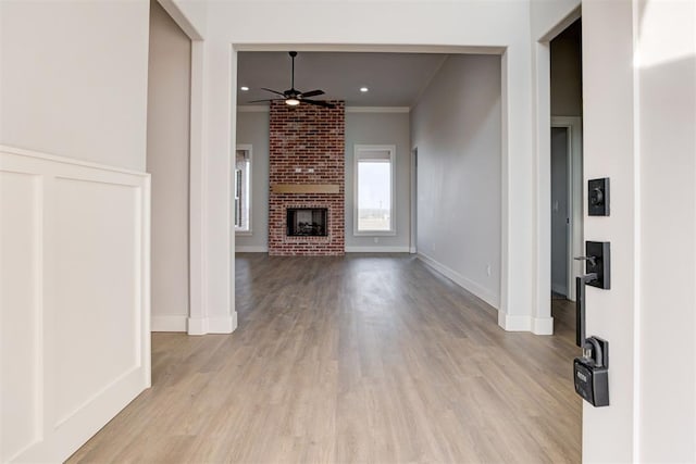 4337 Pinon Ln, Piedmont, OK 73078 - unfurnished living room featuring a ceiling fan, light wood-style flooring, ornamental molding, and a brick fireplace