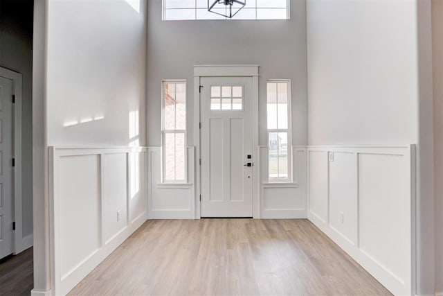 4337 Pinon Ln, Piedmont, OK 73078 - entrance foyer featuring a decorative wall, light wood-type flooring, a towering ceiling, a wainscoted wall, and healthy amount of natural light