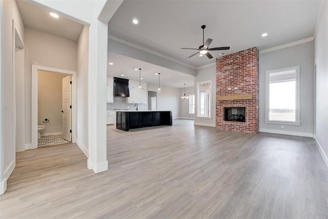 4337 Pinon Ln, Piedmont, OK 73078 - unfurnished living room featuring a ceiling fan, light wood-type flooring, ornamental molding, recessed lighting, and a brick fireplace