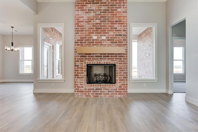 4337 Pinon Ln, Piedmont, OK 73078 - unfurnished living room with a chandelier, wood finished floors, a fireplace, and healthy amount of natural light
