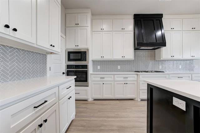 4337 Pinon Ln, Piedmont, OK 73078 - kitchen with appliances with stainless steel finishes, range hood, decorative backsplash, light countertops, and white cabinetry