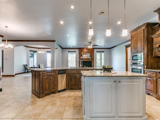 13705 Cascata Strada St, Oklahoma City, OK 73170 - kitchen with stainless steel appliances, a kitchen island, ornamental molding, a ceiling fan, and open floor plan