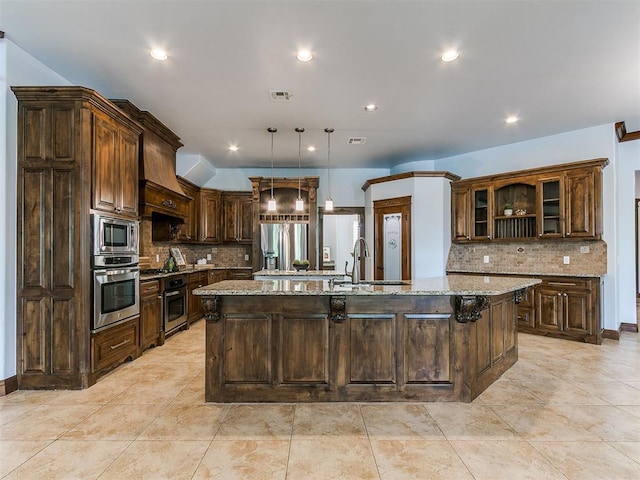 13705 Cascata Strada St, Oklahoma City, OK 73170 - kitchen with stainless steel appliances, a large island, tasteful backsplash, light stone countertops, and recessed lighting