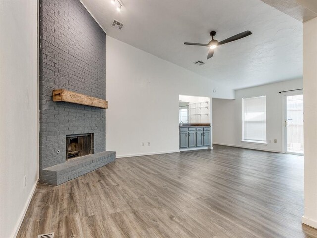 704 NW 137th St, Edmond, OK 73013 - unfurnished living room featuring a ceiling fan, wood finished floors, lofted ceiling, and a fireplace