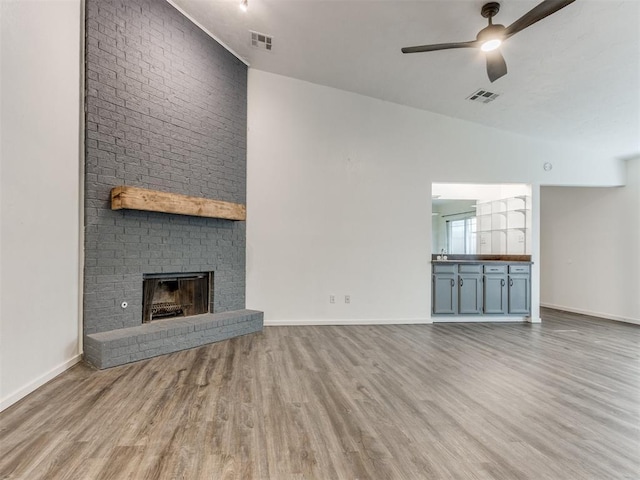 704 NW 137th St, Edmond, OK 73013 - unfurnished living room with ceiling fan, wood finished floors, and a brick fireplace