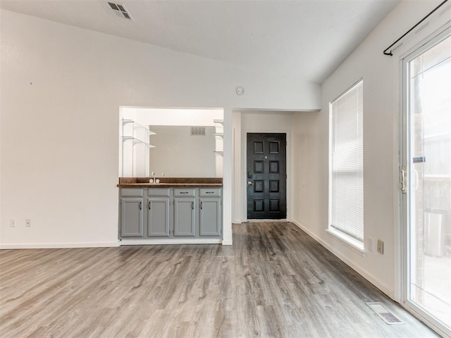 704 NW 137th St, Edmond, OK 73013 - unfurnished living room featuring wood finished floors, healthy amount of natural light, and lofted ceiling
