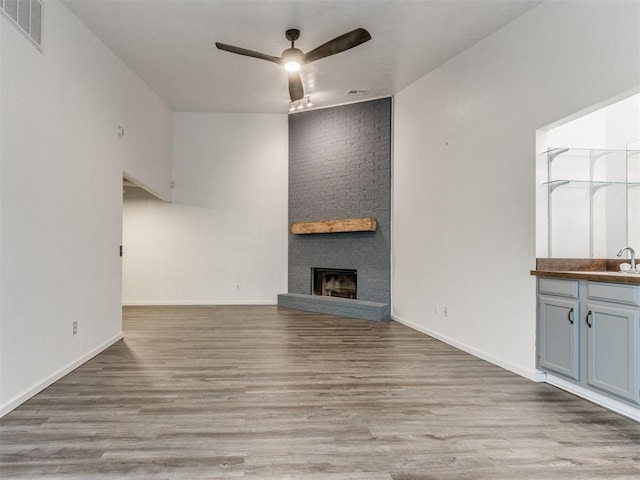 704 NW 137th St, Edmond, OK 73013 - unfurnished living room featuring ceiling fan, a fireplace, and wood finished floors