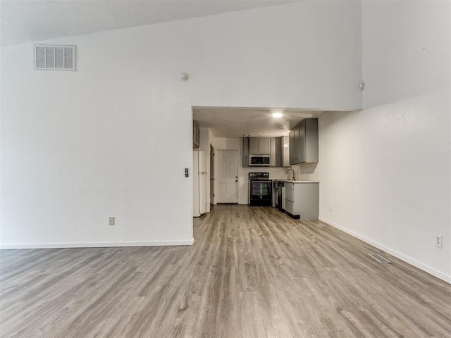 704 NW 137th St, Edmond, OK 73013 - unfurnished living room with light wood-style floors and baseboards