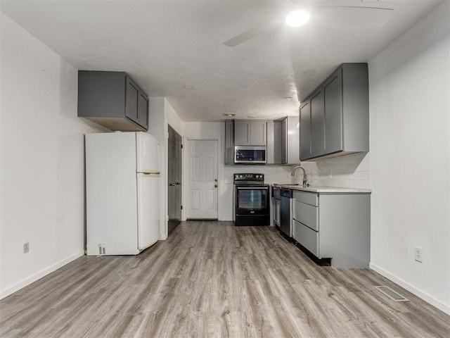 704 NW 137th St, Edmond, OK 73013 - kitchen featuring stainless steel appliances, gray cabinetry, light wood finished floors, a ceiling fan, and light countertops
