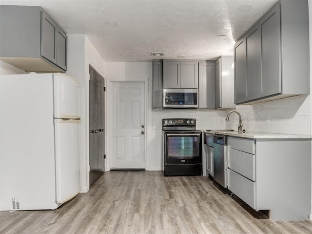 704 NW 137th St, Edmond, OK 73013 - kitchen featuring stainless steel appliances, gray cabinets, light wood finished floors, and light countertops