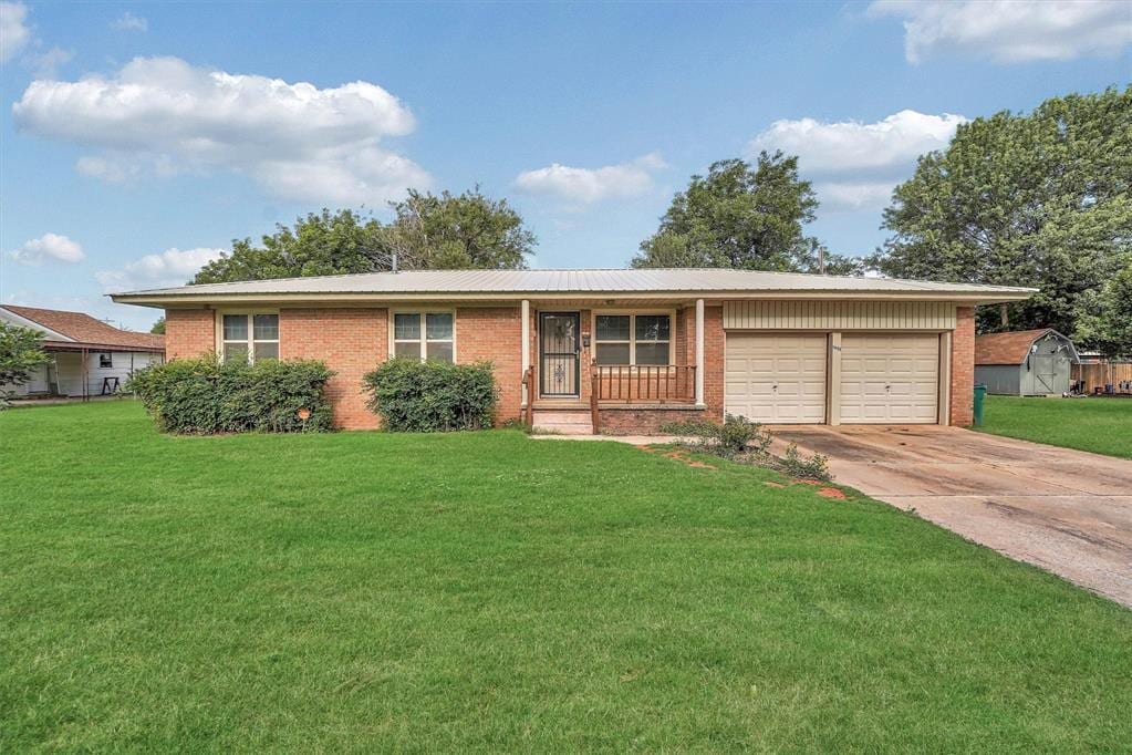 1905 N Oregon Ave, Mangum, OK 73554 - ranch-style home featuring brick siding, a garage, driveway, and a front lawn
