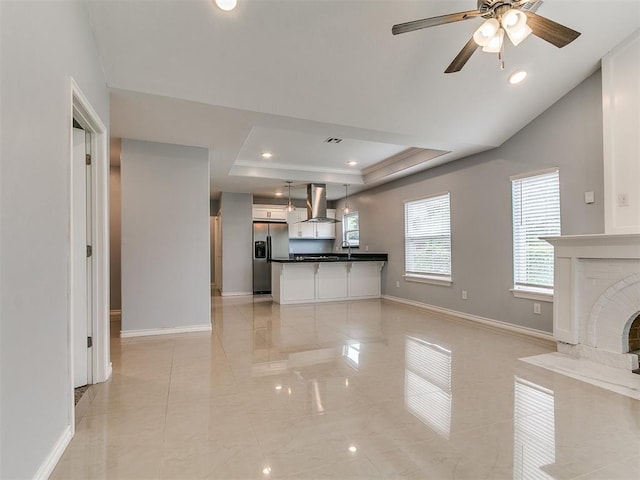 2248 NW 22nd St, Oklahoma City, OK 73107 - unfurnished living room with a tray ceiling, a ceiling fan, a fireplace, light marble finish flooring, and recessed lighting