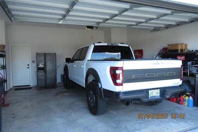 15901 Sarno Ln, Edmond, OK 73013 - garage featuring a garage door opener and black refrigerator with ice dispenser