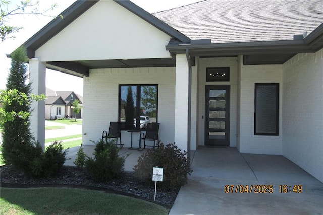 15901 Sarno Ln, Edmond, OK 73013 - doorway to property featuring a porch, brick siding, and a shingled roof