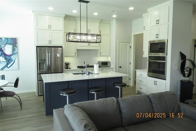 15901 Sarno Ln, Edmond, OK 73013 - kitchen featuring stainless steel appliances, open floor plan, backsplash, white cabinets, and recessed lighting