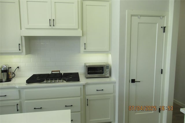 15901 Sarno Ln, Edmond, OK 73013 - kitchen with backsplash, light countertops, white cabinets, and stainless steel gas stovetop