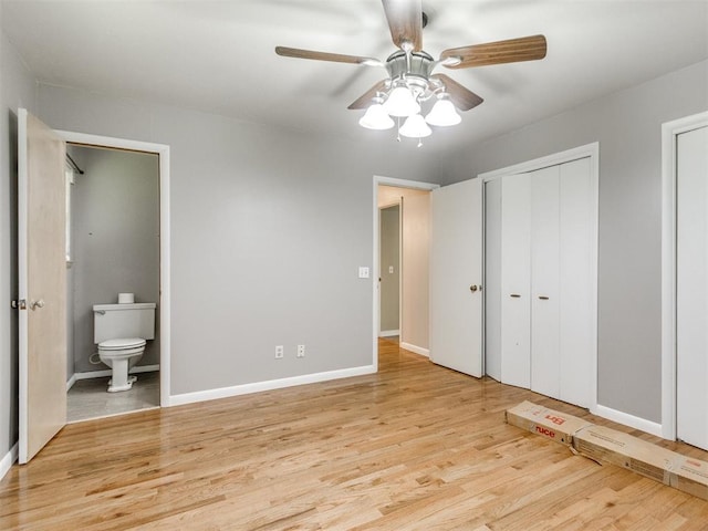 119 Thompson Dr, Moore, OK 73160 - unfurnished bedroom featuring wood finished floors, ensuite bathroom, ceiling fan, and two closets