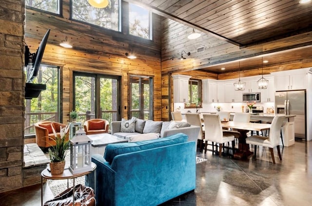 2105 Pine Hills Rd, Broken Bow, OK 74728 - living area featuring plenty of natural light, wood walls, a high ceiling, finished concrete floors, and wooden ceiling