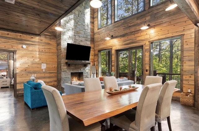 2105 Pine Hills Rd, Broken Bow, OK 74728 - dining area with wooden walls, high vaulted ceiling, finished concrete flooring, a fireplace, and wooden ceiling