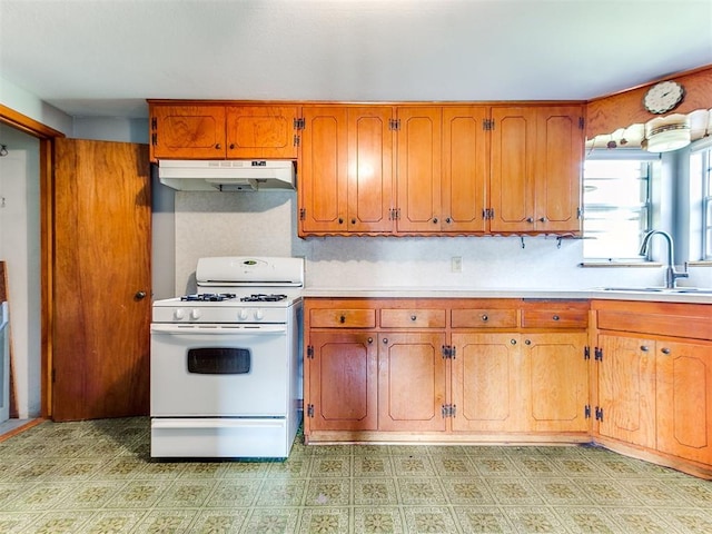 3240 SW 119th St, Oklahoma City, OK 73170 - kitchen with gas range gas stove, under cabinet range hood, light countertops, and brown cabinetry