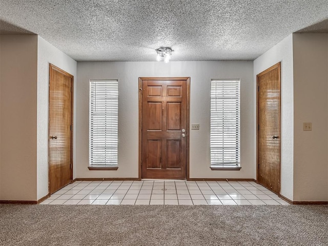 4812 Hunton Ter, Yukon, OK 73099 - entryway with light tile patterned floors, a textured ceiling, light carpet, and a textured wall