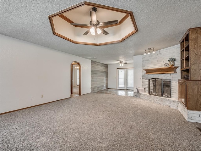 4812 Hunton Ter, Yukon, OK 73099 - unfurnished living room featuring ceiling fan, a textured ceiling, carpet, a fireplace, and arched walkways
