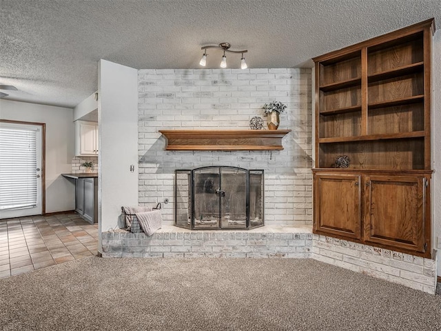 4812 Hunton Ter, Yukon, OK 73099 - unfurnished living room with a brick fireplace, light carpet, a textured ceiling, light tile patterned floors, and track lighting
