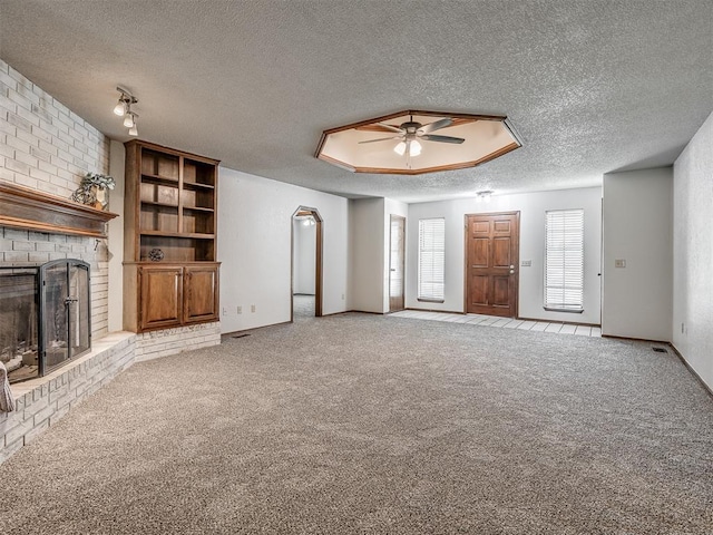 4812 Hunton Ter, Yukon, OK 73099 - unfurnished living room featuring a textured ceiling, ceiling fan, a fireplace, and carpet