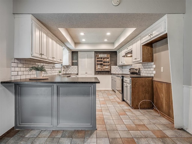 4812 Hunton Ter, Yukon, OK 73099 - kitchen featuring electric range, dark countertops, a peninsula, backsplash, and under cabinet range hood