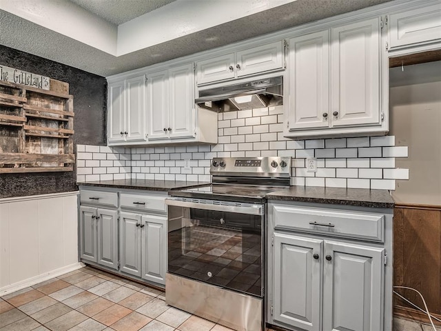 4812 Hunton Ter, Yukon, OK 73099 - kitchen featuring stainless steel electric range, under cabinet range hood, a wainscoted wall, a textured ceiling, and decorative backsplash