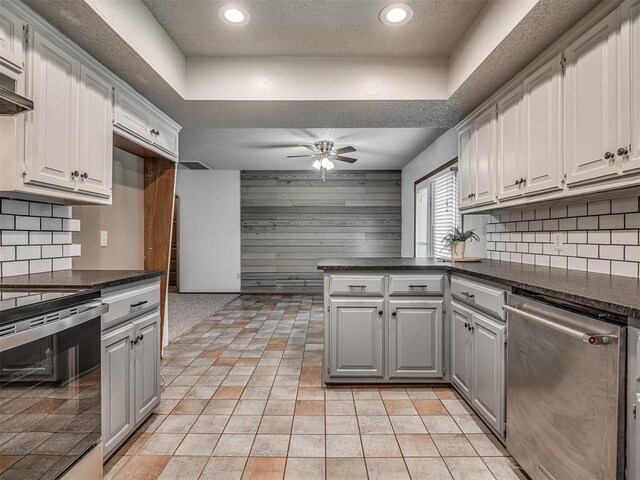 4812 Hunton Ter, Yukon, OK 73099 - kitchen featuring appliances with stainless steel finishes, a peninsula, dark countertops, a ceiling fan, and tasteful backsplash