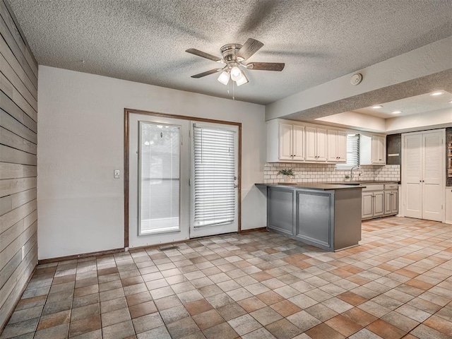 4812 Hunton Ter, Yukon, OK 73099 - kitchen featuring a peninsula, backsplash, ceiling fan, a textured ceiling, and dark countertops