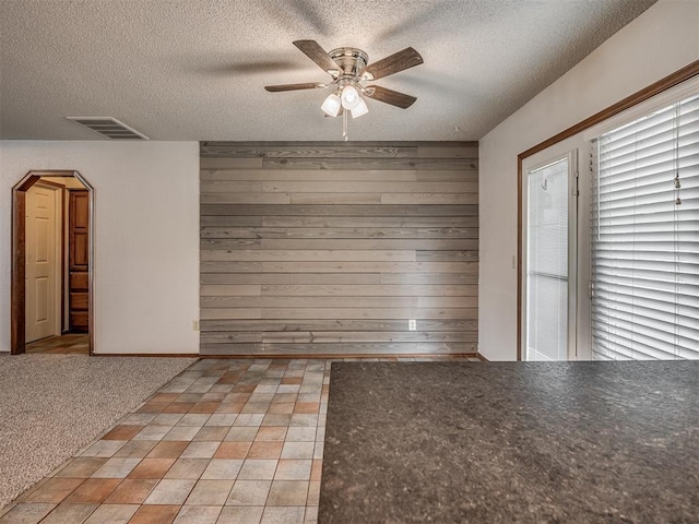 4812 Hunton Ter, Yukon, OK 73099 - unfurnished dining area featuring ceiling fan, wood walls, a textured ceiling, and arched walkways