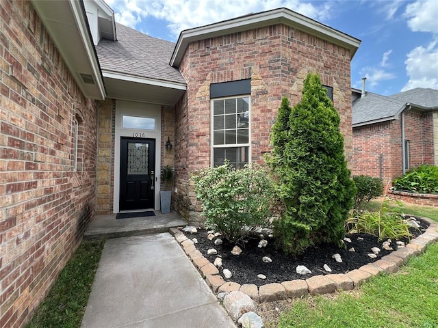 1016 Erinova Dr, Yukon, OK 73099 - view of exterior entry featuring a shingled roof and brick siding