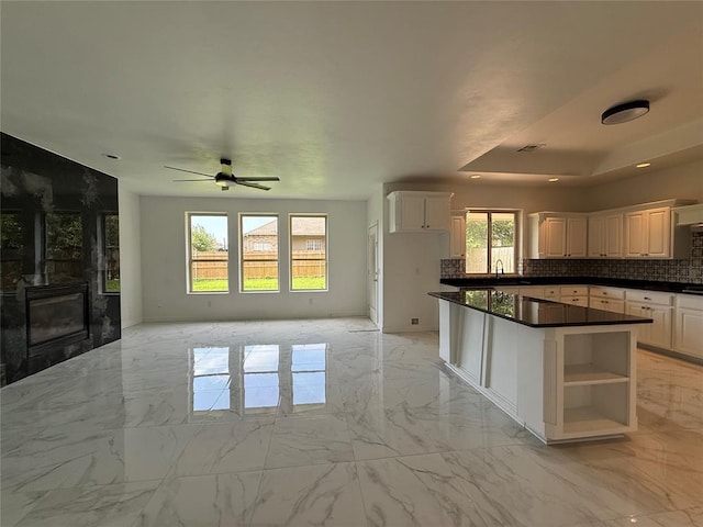 1016 Erinova Dr, Yukon, OK 73099 - kitchen featuring backsplash, dark countertops, light marble finish flooring, ceiling fan, and a center island