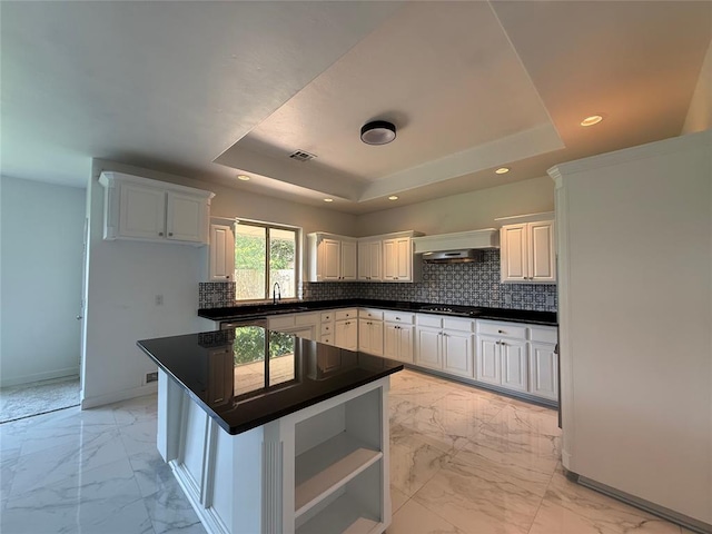 1016 Erinova Dr, Yukon, OK 73099 - kitchen with light marble finish flooring, a tray ceiling, dark countertops, tasteful backsplash, and recessed lighting