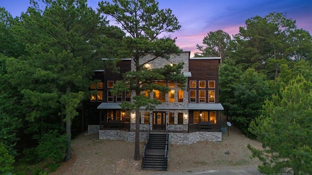 229 Sweet Gum Trl, Broken Bow, OK 74728 - back of house at dusk with a porch, stone siding, and stairs