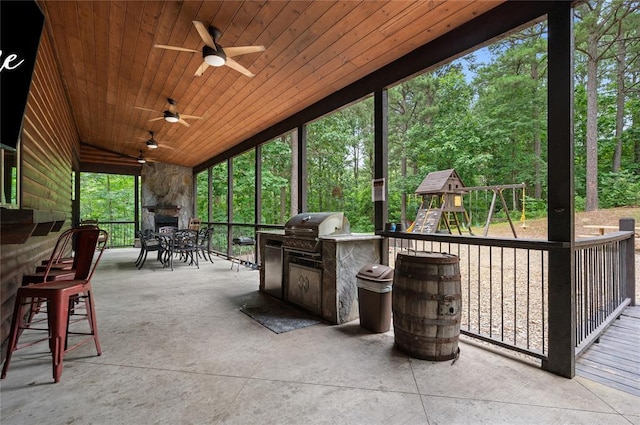 229 Sweet Gum Trl, Broken Bow, OK 74728 - view of patio / terrace featuring an outdoor stone fireplace, exterior kitchen, ceiling fan, and a playground