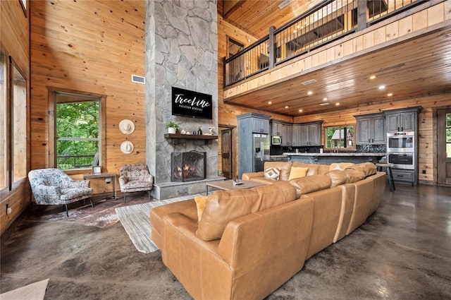 229 Sweet Gum Trl, Broken Bow, OK 74728 - living room with wood ceiling, plenty of natural light, wood walls, a towering ceiling, and a fireplace