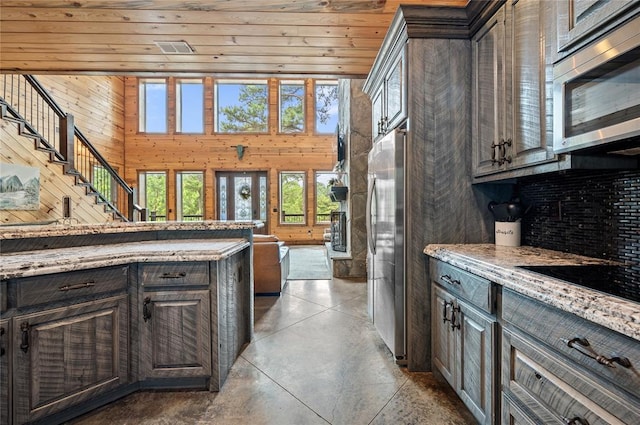 229 Sweet Gum Trl, Broken Bow, OK 74728 - kitchen with stainless steel appliances, finished concrete flooring, wood walls, light stone countertops, and open floor plan