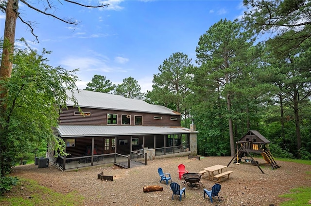 229 Sweet Gum Trl, Broken Bow, OK 74728 - back of property with a fire pit, a playground, a sunroom, a metal roof, and a chimney